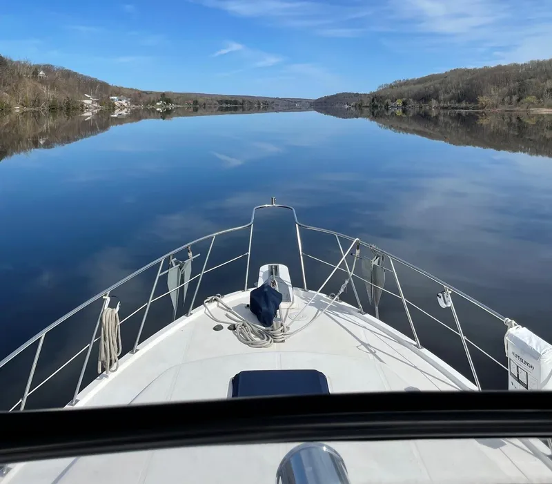 Slide: The Image of 1989 Marine Trader 47 CMY cruising on a calm, reflective lake under a clear blue sky. - 4