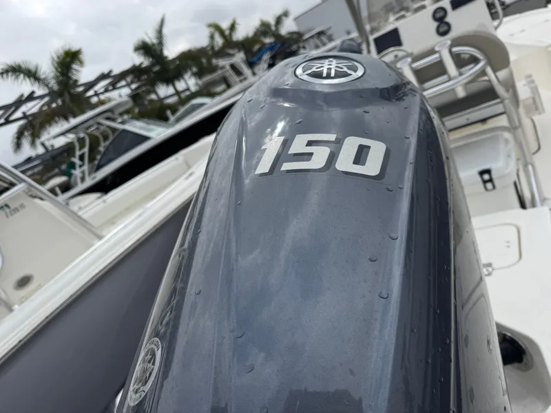 Slide: The Image of Close-up of a 2025 Key West 210 Bay Reef boat engine, marked "150," with palm trees in background. - 6
