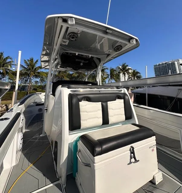 Slide: The Image of 2019 Nor-Tech 340 Sport Center Console boat with seating, palm trees, and clear sky. - 5