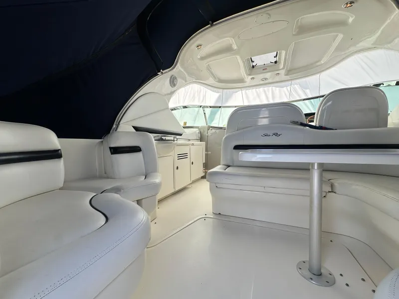 Slide: The Image of 2007 Sea Ray 380 Sundancer interior with white seating and table, under a dark canopy. - 6