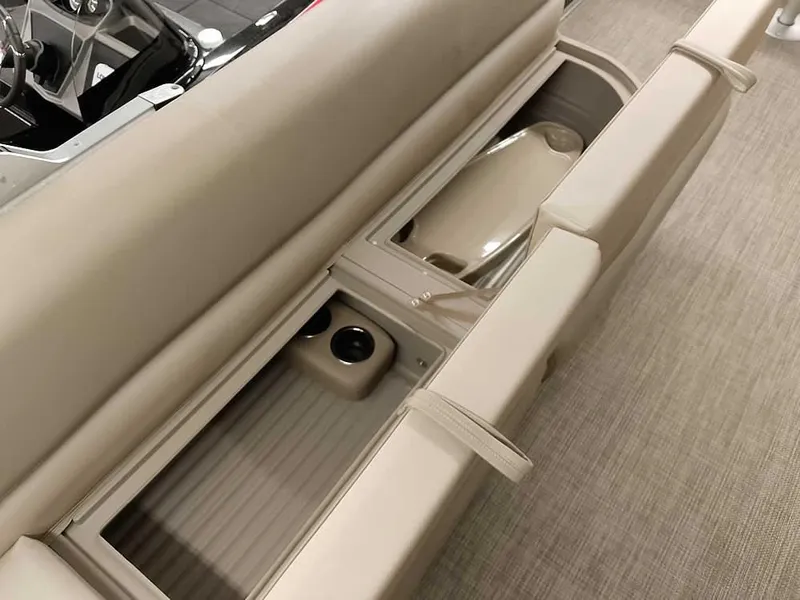 Slide: The Image of 2023 Ranger Reata 200F Pontoon interior storage compartment with cup holders and beige seating. - 13