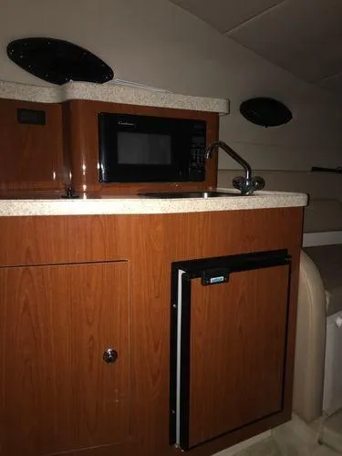 Slide: The Image of 2010 Regal 2700 Commodore boat interior with kitchenette, microwave, and mini-fridge. - 8