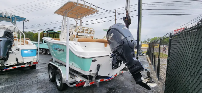 Slide: The Image of 2025 NauticStar 212 Legacy boat on trailer, featuring outboard motor and teal accents. - 2