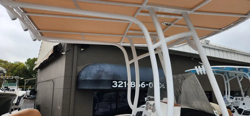 Slide: The Image of 2025 NauticStar 212 Legacy boat with canopy, parked near a building. - 5