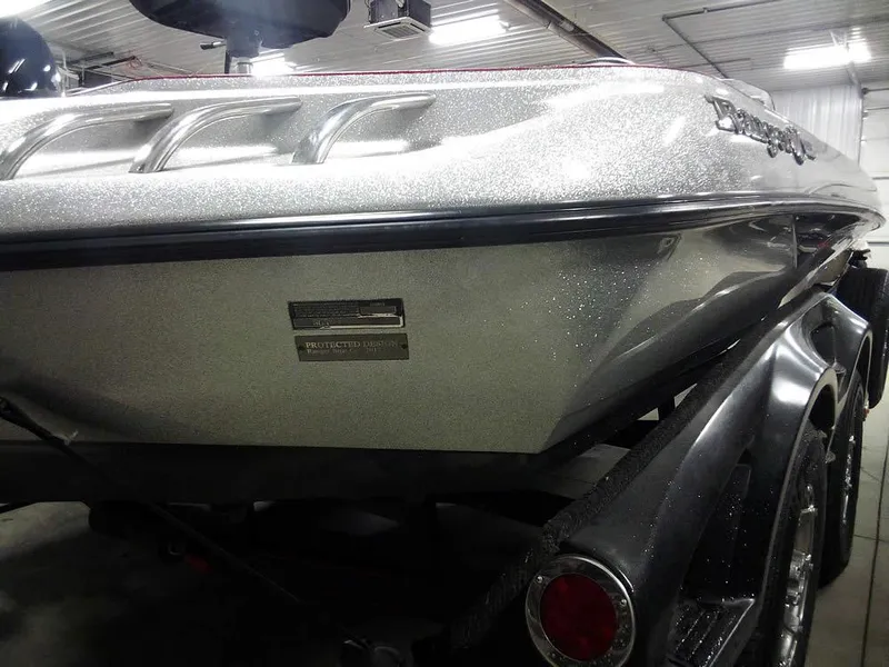 Slide: The Image of 2013 Ranger Z520C Comanche boat in a garage, showcasing sleek design and metallic finish. - 12