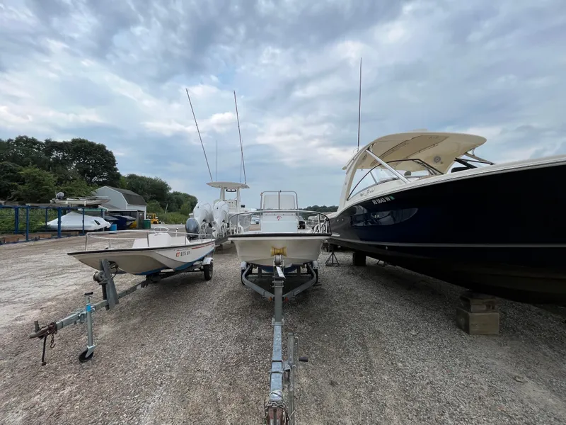 Slide: The Image of Three boats, including a 1994 Boston Whaler 15 Dauntless, parked on a gravel lot. - 2