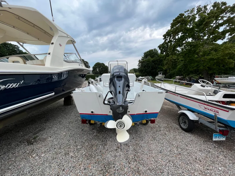 Slide: The Image of 1994 Boston Whaler 15 Dauntless boat, rear view, parked on gravel with other boats. - 5