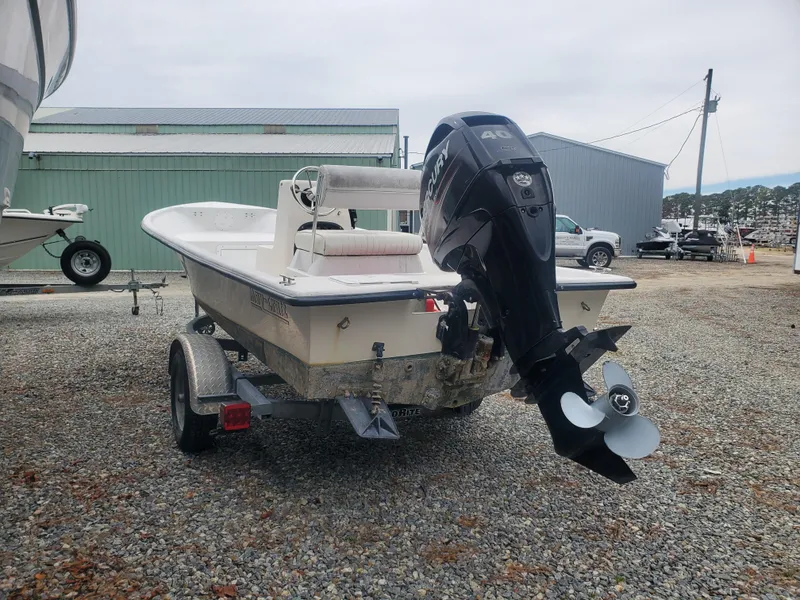 Slide: The Image of 2018 May-Craft 1700 Skiff boat on trailer with outboard motor in a gravel lot. - 2