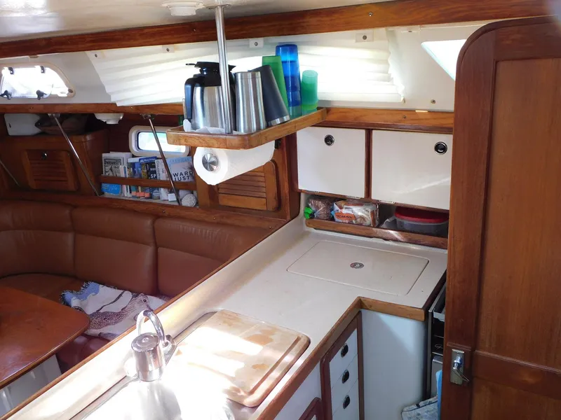 Slide: The Image of Interior of 1998 Catalina 34 Mark II sailboat, featuring a cozy kitchen and seating area. - 21