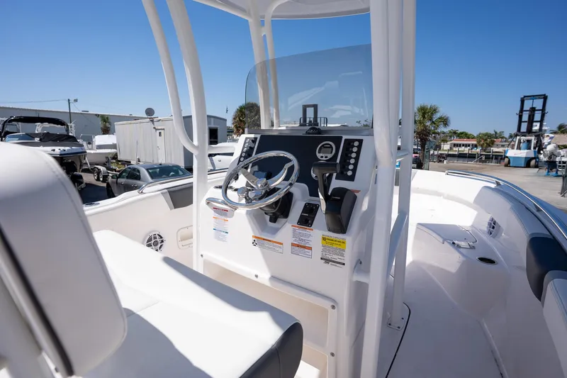 Slide: The Image of 2025 Robalo R222 boat cockpit with steering wheel and control panel, docked under clear sky. - 10