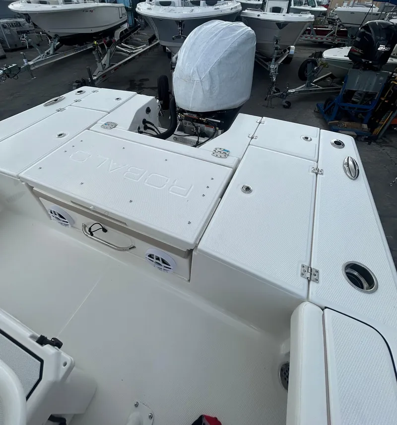 Slide: The Image of 2025 Robalo 246 Cayman boat interior with covered engine, docked among other boats. - 10
