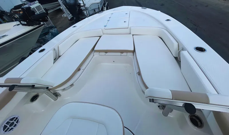 Slide: The Image of 2025 Robalo 246 Cayman boat interior with white cushioned seating and fishing rod holders. - 3