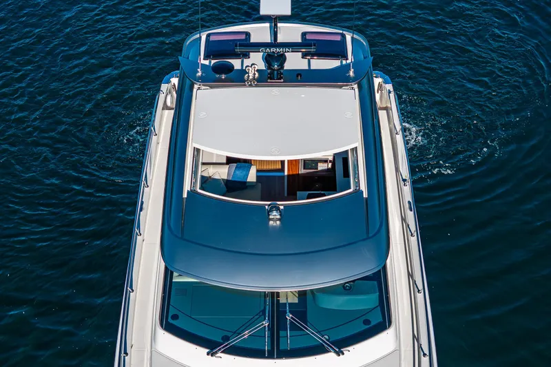 Slide: The Image of 2025 Riviera 4600 Sport Yacht cruising on open water, aerial view. - 10