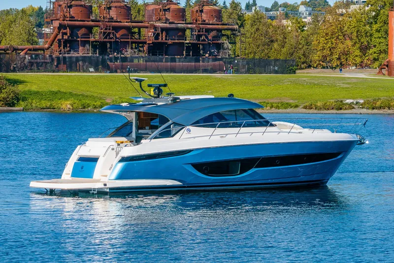 Slide: The Image of 2025 Riviera 4600 Sport Yacht on a serene lake with industrial backdrop. - 15