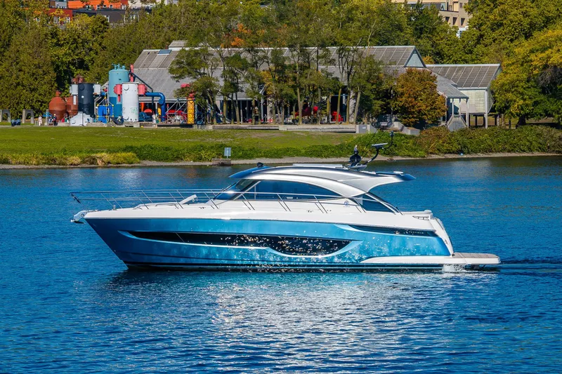 Slide: The Image of 2025 Riviera 4600 Sport Yacht cruising on a serene lake with lush greenery backdrop. - 19