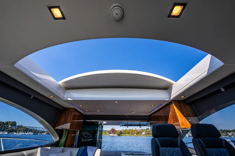 Slide: The Image of Interior view of 2025 Riviera 4600 Sport Yacht with open sunroof and scenic water backdrop. - 26