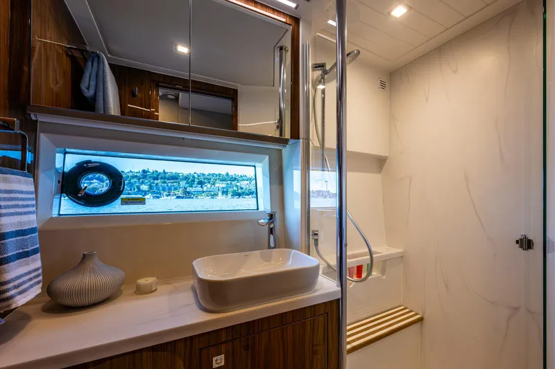 Slide: The Image of Luxurious bathroom in 2025 Riviera 4600 Sport Yacht with modern fixtures and scenic window view. - 47