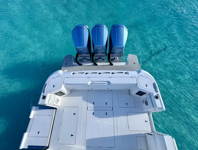 Slide: The Image of 2023 Intrepid 427 Nomad SE boat with triple engines on clear blue water. - 13