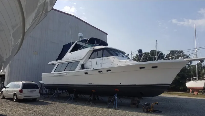 The Image of 1998 Bayliner 4788 Pilot House Motoryacht on dry dock beside a building. - 0