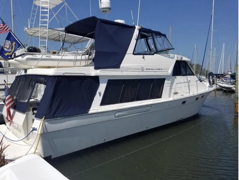 Slide: The Image of 1998 Bayliner 4788 Pilot House Motoryacht docked in a marina, featuring blue canvas covers. - 2