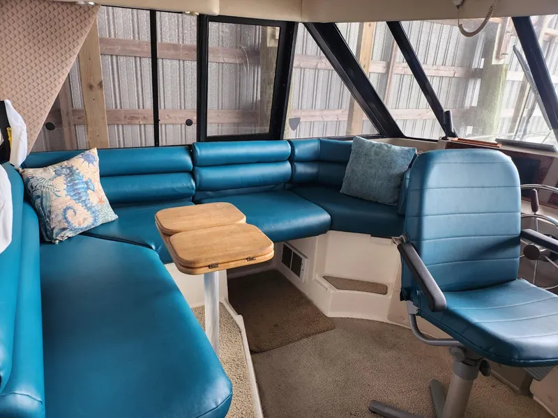 Slide: The Image of 1998 Bayliner 4788 Pilot House Motoryacht interior with blue seating and wooden table. - 23