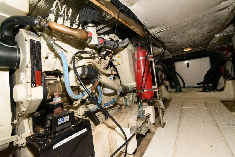Slide: The Image of Engine room of 1998 Bayliner 4788 Pilot House Motoryacht, showcasing mechanical components and fire extinguisher. - 26