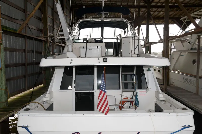 Slide: The Image of 1998 Bayliner 4788 Pilot House Motoryacht docked in a covered marina, rear view. - 4