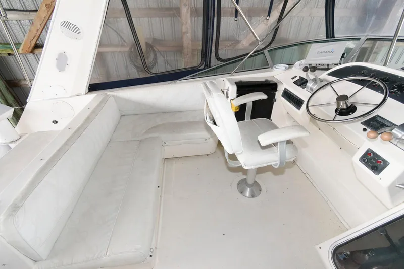 Slide: The Image of 1998 Bayliner 4788 Pilot House Motoryacht helm with white seating and steering wheel. - 7