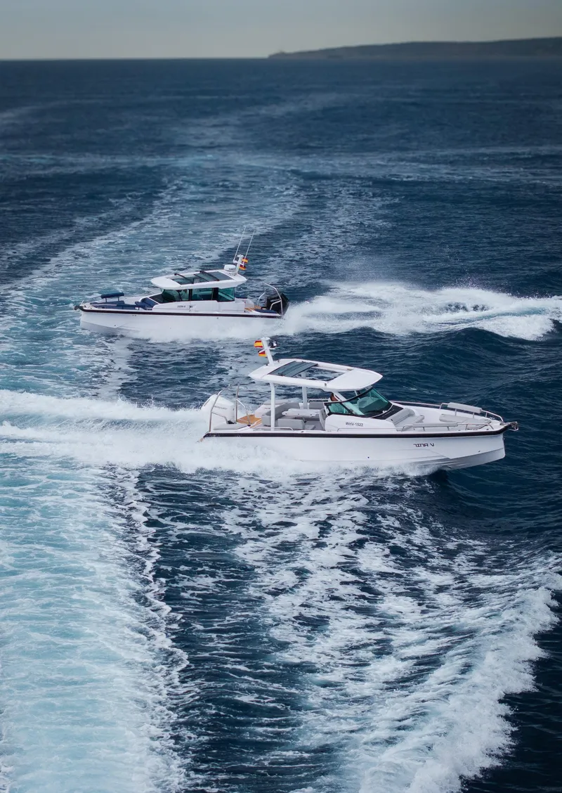 The Image of 2025 Axopar 29 Sun-Top boat cruising on blue ocean with distant bridge view. - 0