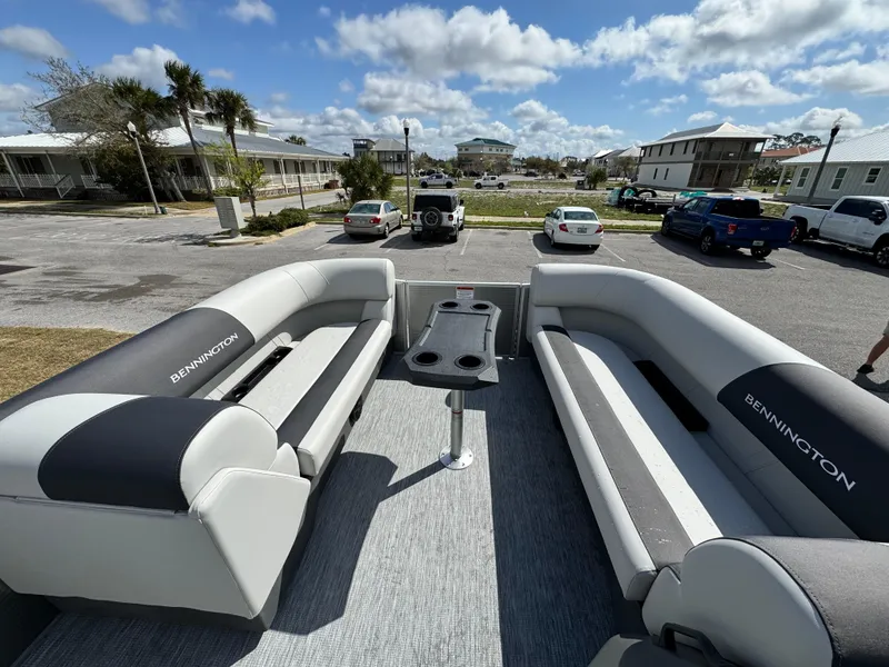 Slide: The Image of 2025 Bennington 22 SSB pontoon boat interior with gray seating and table, parked outdoors. - 13