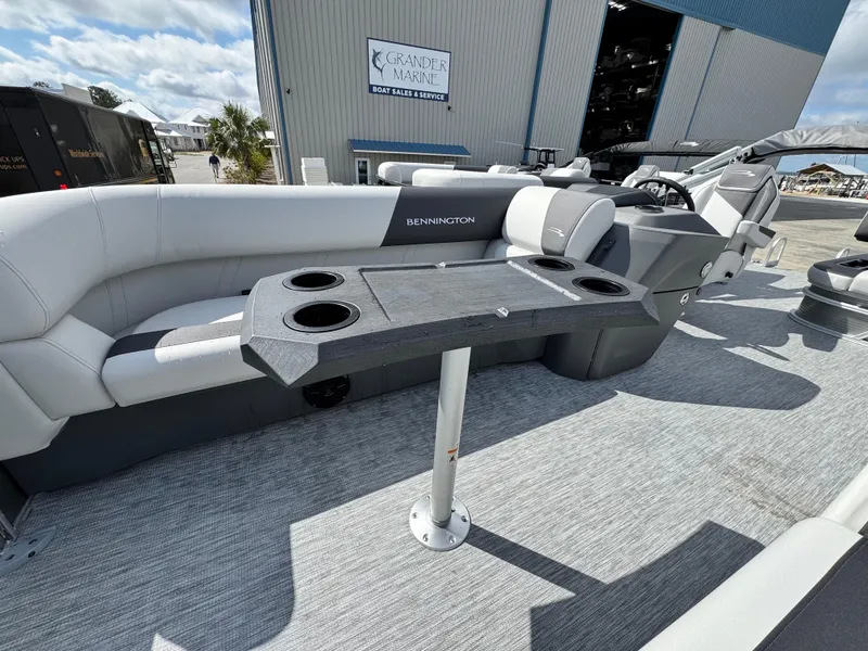 Slide: The Image of 2025 Bennington 22 SSB pontoon boat interior with seating and table, docked at a marina. - 15