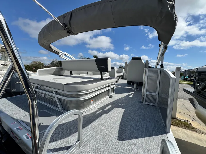 Slide: The Image of 2025 Bennington 22 SSB pontoon boat with spacious seating and canopy under a clear sky. - 6