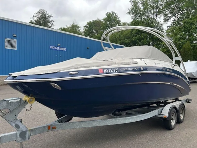 Slide: The Image of 2014 Yamaha 242 Limited S boat on galvanized trailer, parked near blue building. - 10