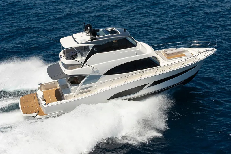Slide: The Image of 2026 Riviera 58 Sports Motor Yacht cruising in a sunny marina setting. - 2
