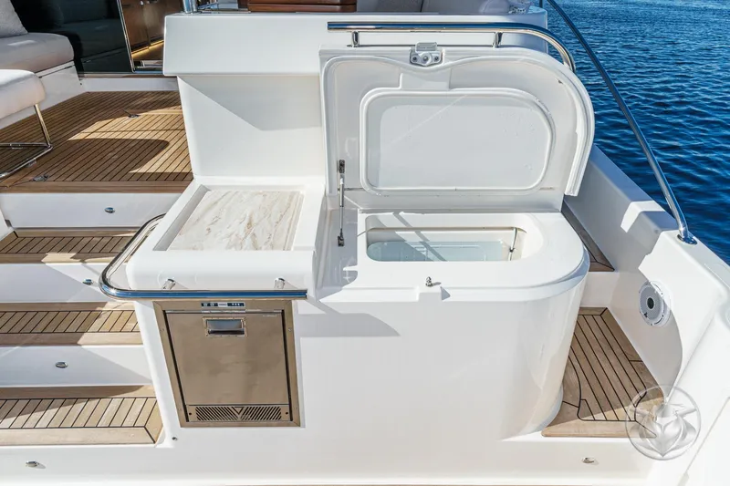 Slide: The Image of 2026 Riviera 58 Sports Motor Yacht deck with open storage compartment and stainless steel accents. - 21