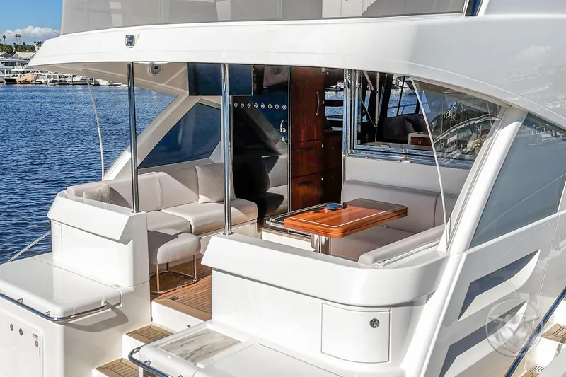 Slide: The Image of 2026 Riviera 58 Sports Motor Yacht, elegant deck with seating and table, docked by the water. - 23
