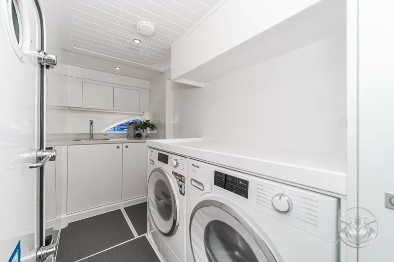 Slide: The Image of Laundry room in 2026 Riviera 58 Sports Motor Yacht with washer, dryer, and sink. - 64