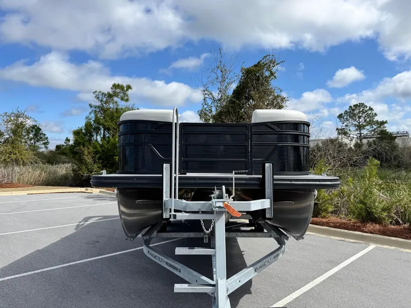 Slide: The Image of 2025 Bennington S Quad Bench 22 SSR pontoon boat on trailer, parked outdoors. - 3