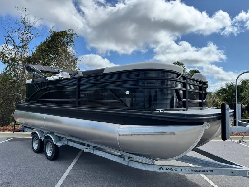 Slide: The Image of 2025 Bennington S Quad Bench 22 SSR pontoon boat on trailer, parked outdoors. - 4