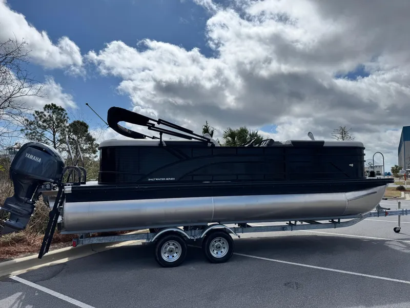 Slide: The Image of 2025 Bennington S Quad Bench 22 SSR pontoon boat on trailer, parked outdoors. - 5