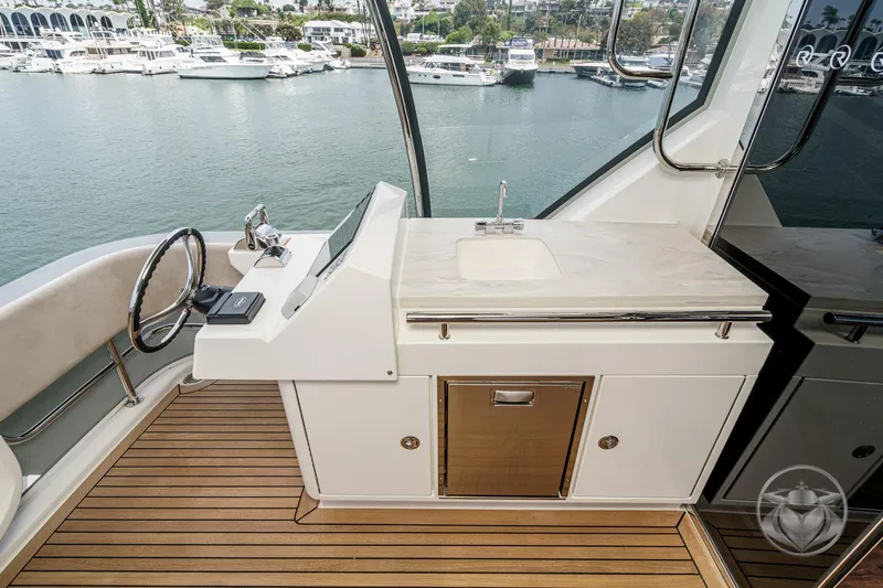 Slide: The Image of 2025 Riviera 64 Sports Motor Yacht helm with sink, overlooking marina. - 25