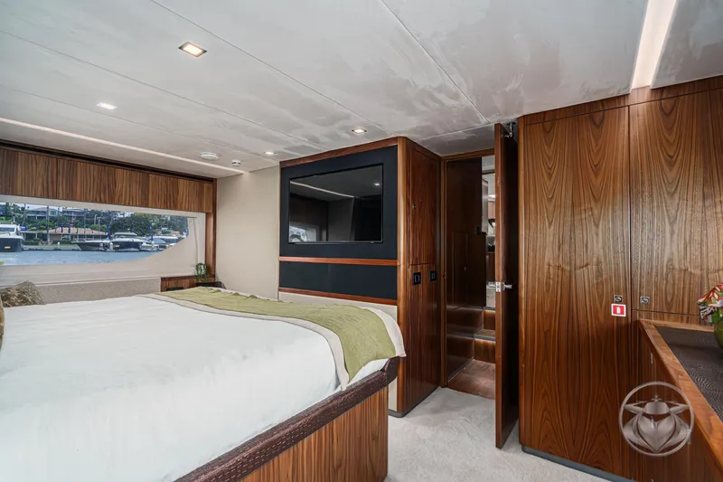 Slide: The Image of Luxurious bedroom interior of 2025 Riviera 64 Sports Motor Yacht with wood paneling and large window. - 45