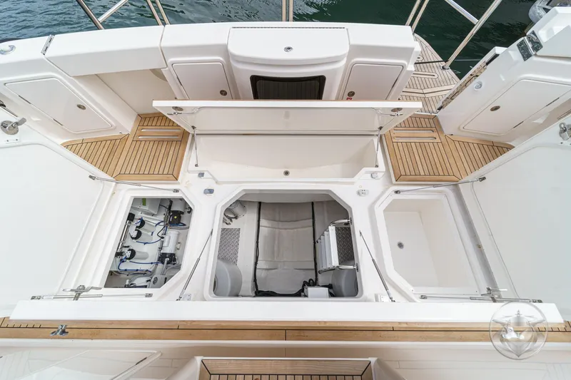 Slide: The Image of 2025 Riviera 64 Sports Motor Yacht deck with open storage compartments and teak flooring. - 55