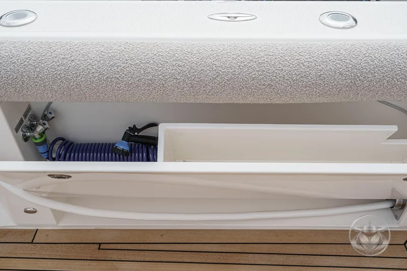 Slide: The Image of Storage compartment on 2025 Riviera 64 Sports Motor Yacht with coiled hose and faucet. - 56