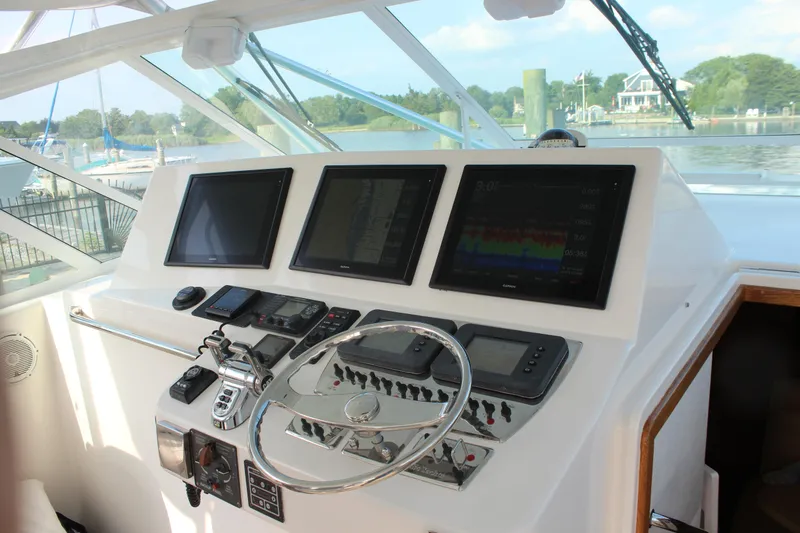 Slide: The Image of Control panel of 2005 Cabo 40 Hardtop Express boat with navigation screens and steering wheel. - 12