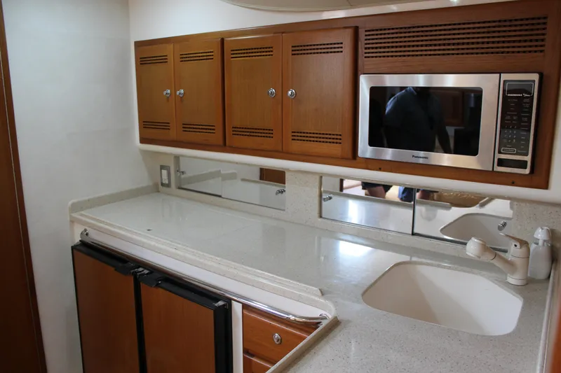 Slide: The Image of 2005 Cabo 40 Hardtop Express kitchen with microwave, sink, and wooden cabinets. - 18