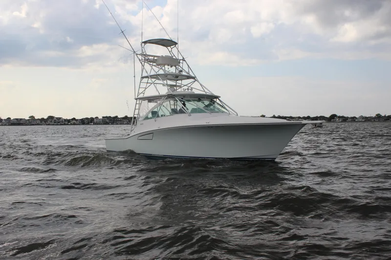 Slide: The Image of 2005 Cabo 40 Hardtop Express boat cruising on open water under cloudy sky. - 2
