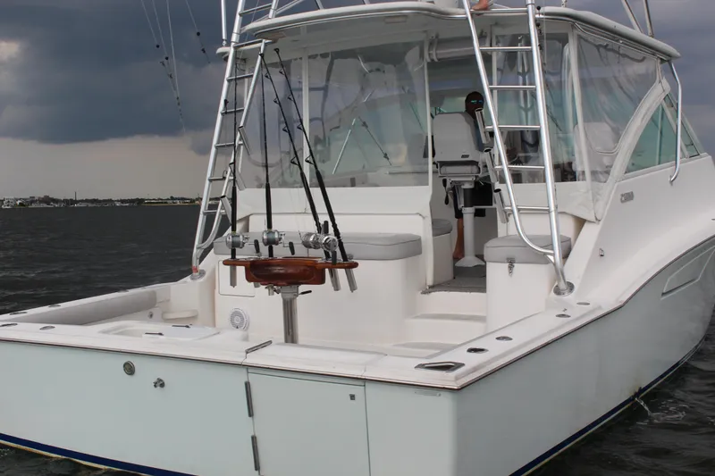 Slide: The Image of 2005 Cabo 40 Hardtop Express boat on water, featuring fishing rods and stormy sky. - 35