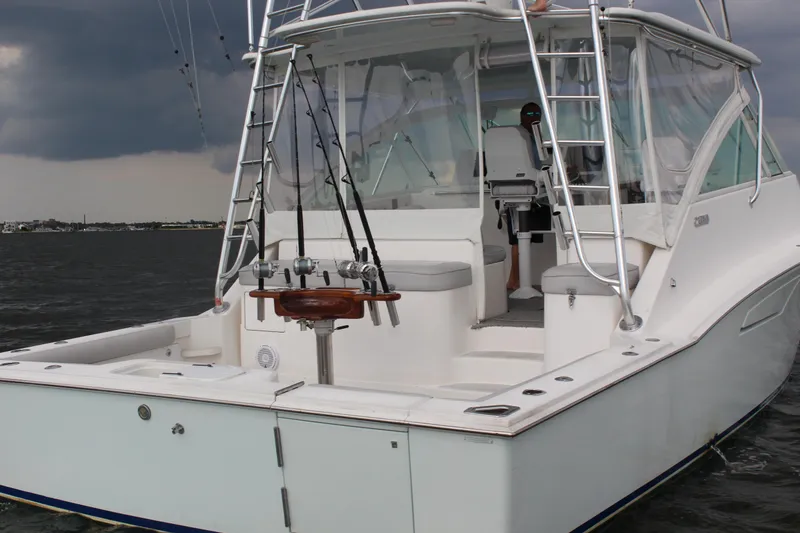 Slide: The Image of 2005 Cabo 40 Hardtop Express boat on water, featuring fishing rods and stormy sky. - 5