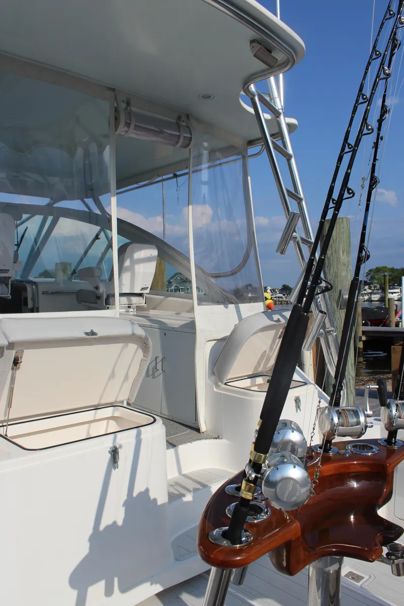 Slide: The Image of 2005 Cabo 40 Hardtop Express yacht with fishing rods, docked under clear blue sky. - 7